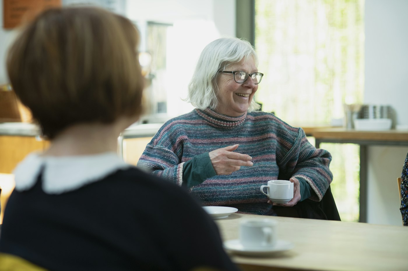 Dame âgée souriante qui discute autour d'un café